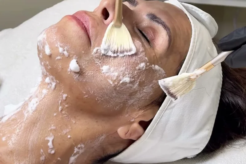 Esthetician brushing a hydrating oxygen foam onto a client's face and neck during the Luxury Oxygen Facial