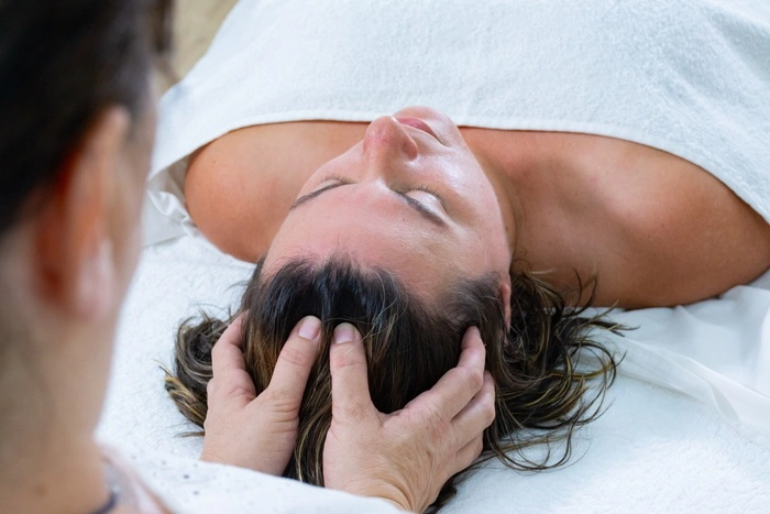 Female masseur giving a hand massage to the scalp of another woman